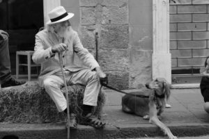 A distinguished senior gentleman in Italy looking down at his pet dog showing the lifelong benefits of pets for seniors